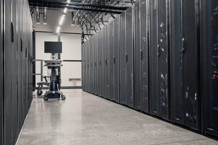 An aisle between rows of server racks in a data room.